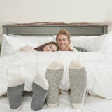 Homme et femme allongés sous une couette en percale avec des chaussettes douillettes